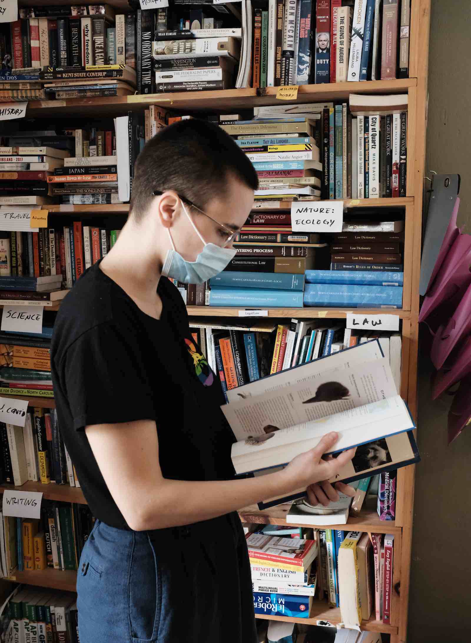 A volunteer wearing a mask inspecting a book.